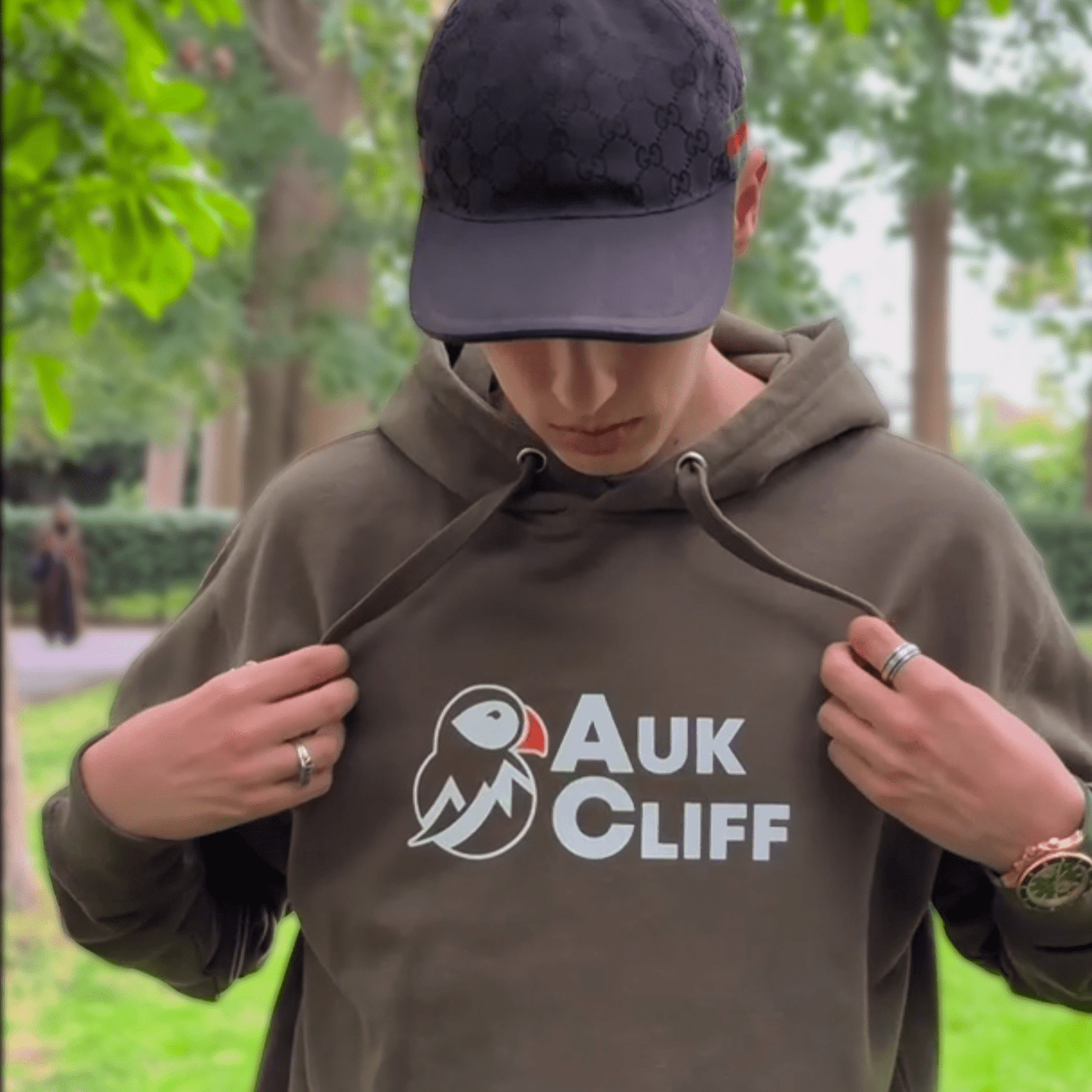 Person wearing a hoodie with 'Auk Cliff' logo outdoors