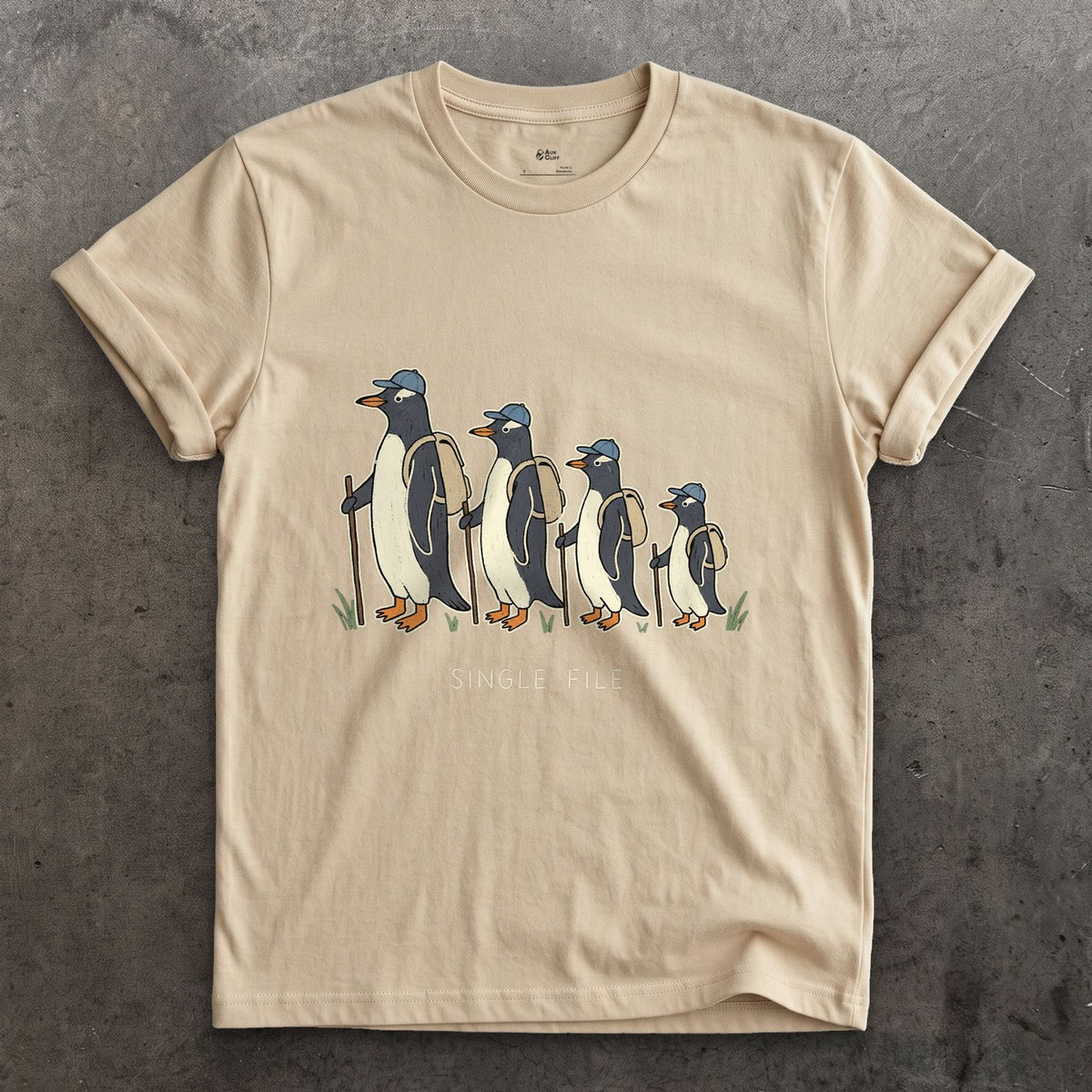Single File, Penguins in the Same Track design on a Sand Gildan Softstyle t-shirt
