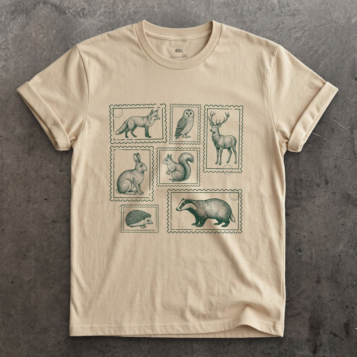 The Whole Woodland Framed Like Stamps design on a Sand Gildan Softstyle t-shirt
