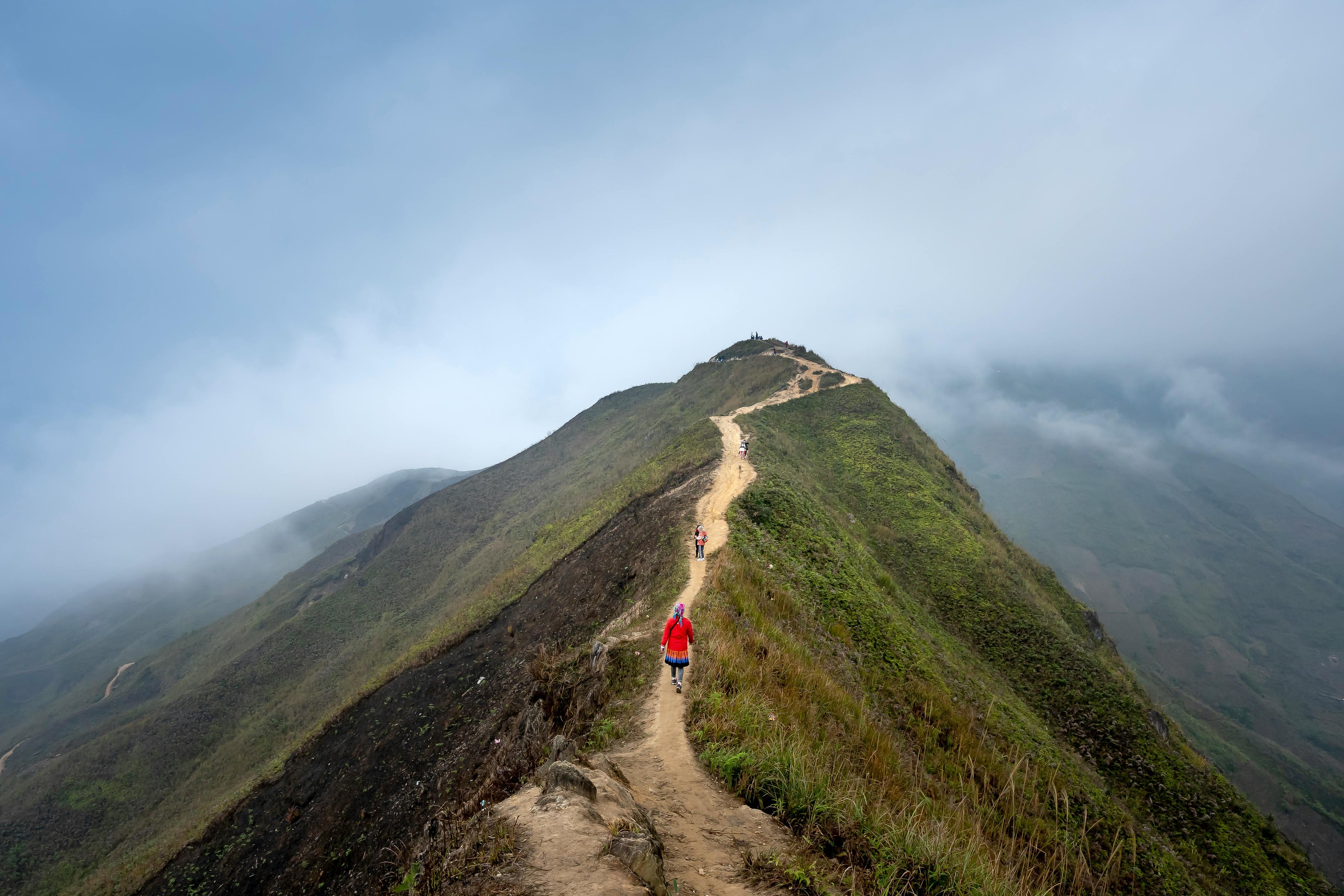 Explore the serene beauty of a misty mountain trail with hikers on a scenic ridge.