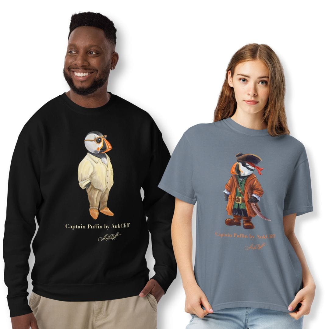Hand-drawn Captain Puffin™ characters by AukCliff wearing adventure-inspired outfits, standing side by side on a clean background — premium Comfort Colors® tees and sweatshirts collection celebrating art, exploration, and timeless style.