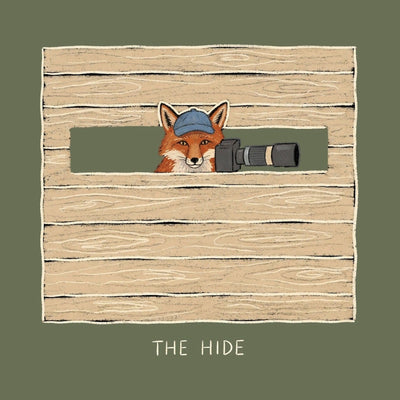 A fox holding a camera lens looking out through the slot of a wooden photography hide, printed on a military green cotton tee