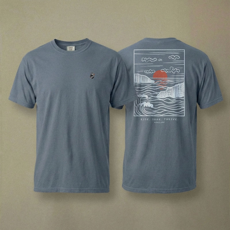 AukCliff Ocean Sunset Waves tee in Blue Jean, hand-drawn sunset and waves line art across the back