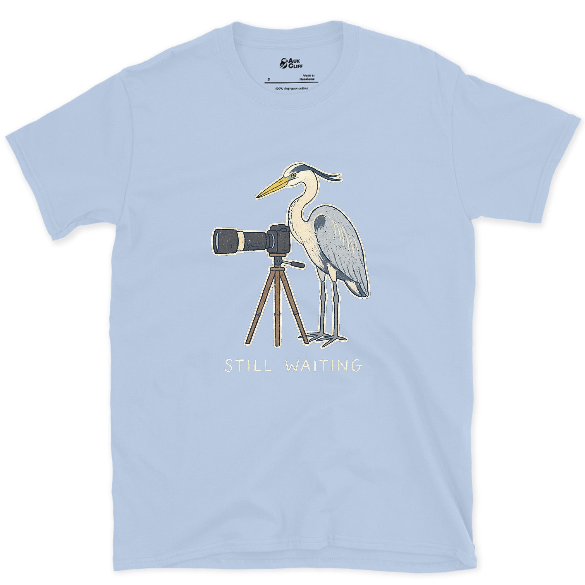 Still Waiting on the Tripod, a Heron Habit design on a Light Blue Gildan Softstyle t-shirt